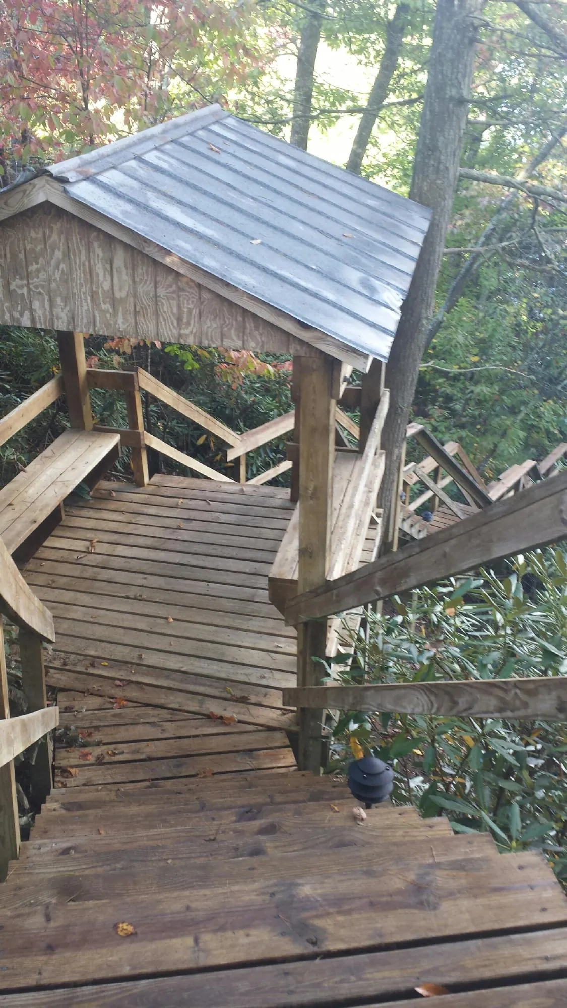 Metal roofed shelter over wooden steps on a wooded walkway — Skylight Repair & Installation work by our crew in Brownsville